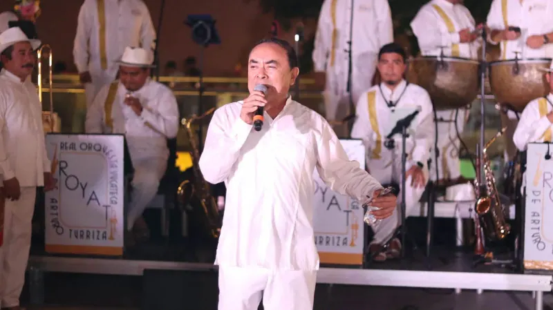 Un cantante con micrófono frente a la orquesta y sus atriles ROYAT en el Palacio de la Música
