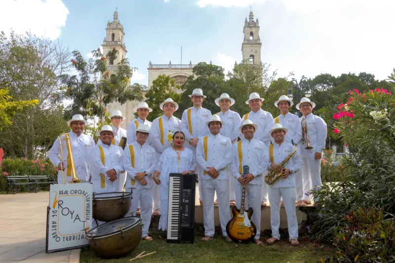 La orquesta completa posa frente a una catedral
